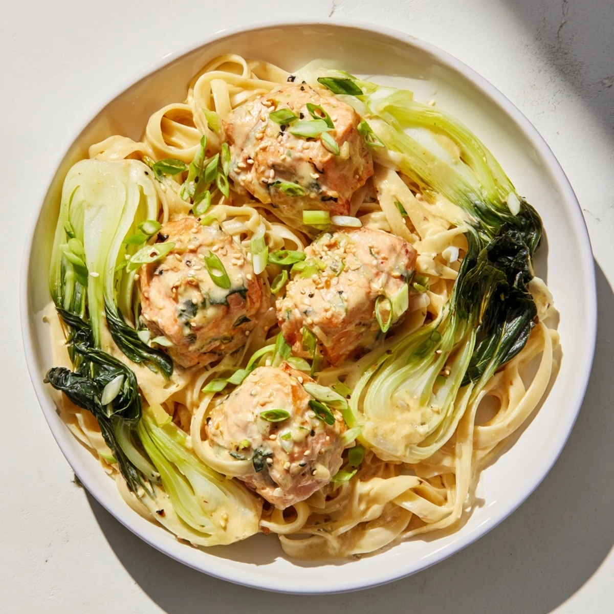 Creamy miso butter salmon pasta, served hot, with glistening sauce and fresh scallions on top.