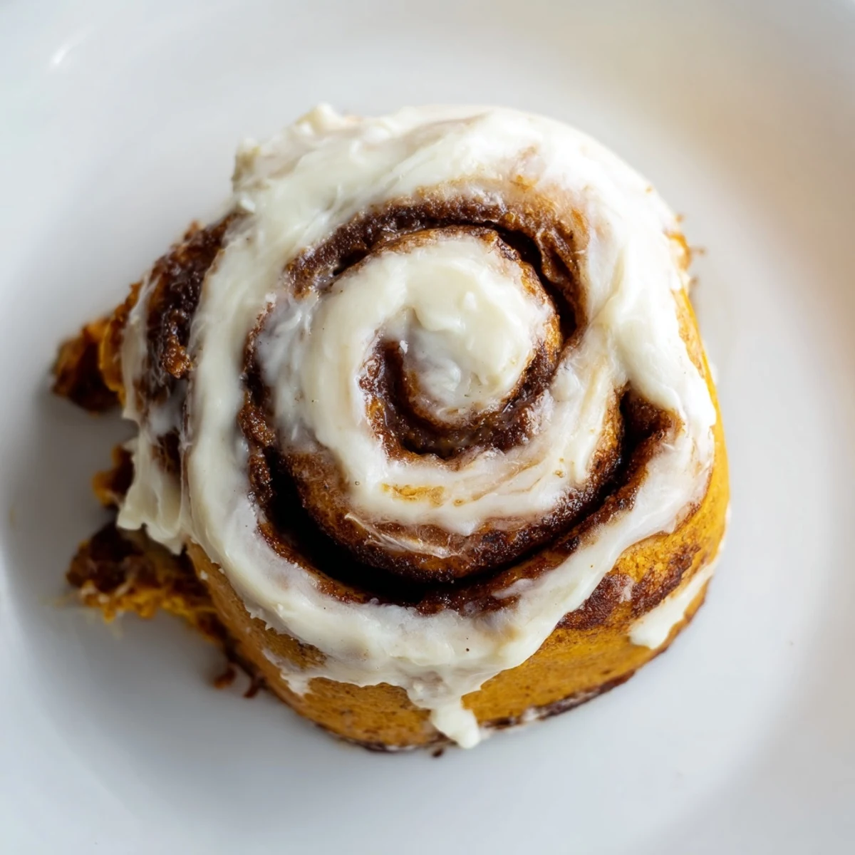 Warm pumpkin cinnamon rolls with velvety cream cheese frosting, perfectly paired with a steaming mug of coffee.