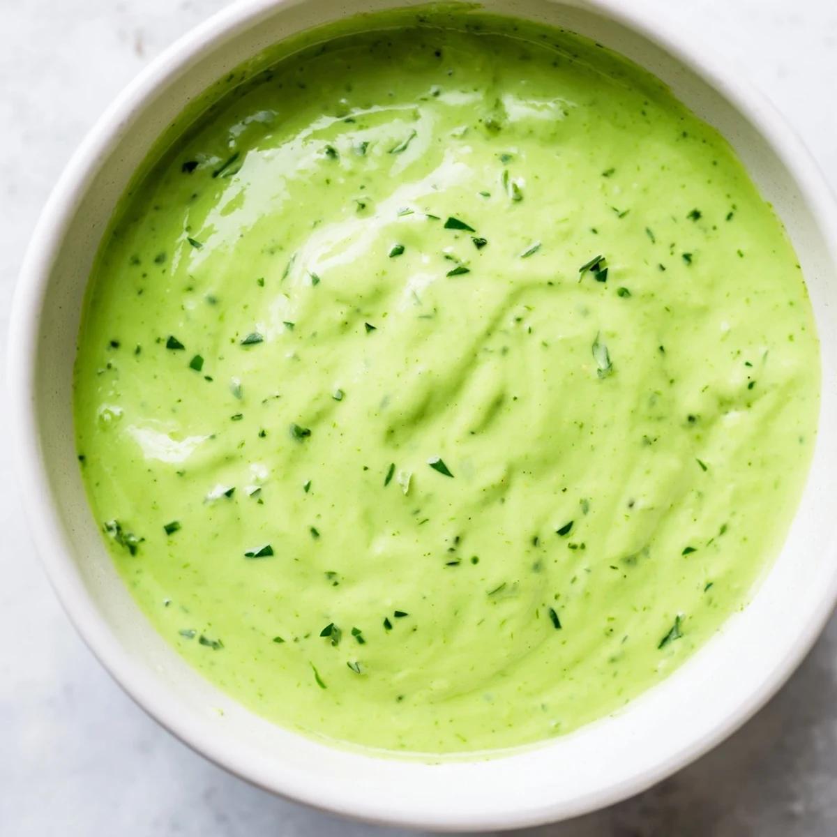 Freshly blended Green Goddess Dressing with a smooth texture and visible flecks of herbs, ready to be served on a vegetable platter.