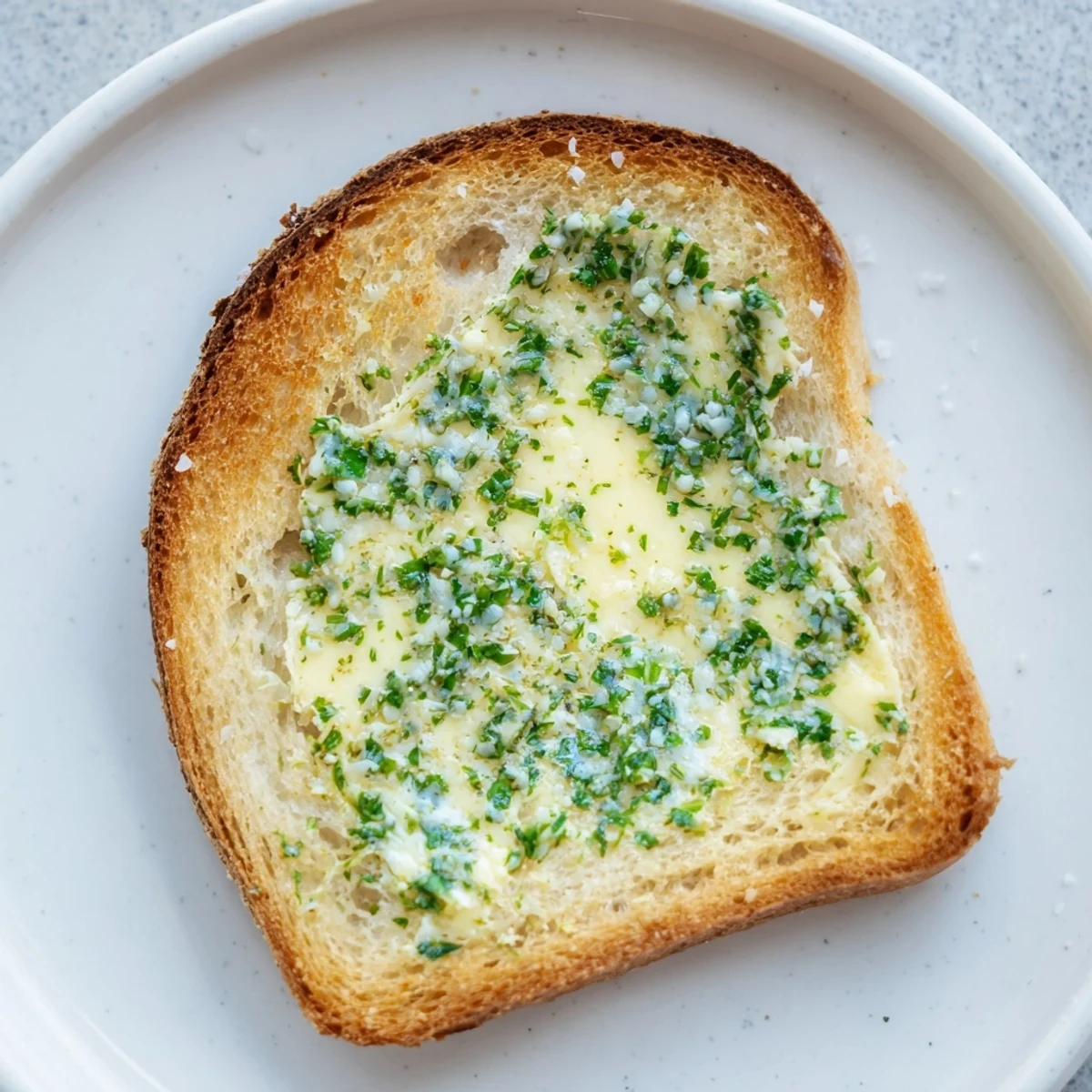 Warm Herb Butter Toast with crunchy edges, served on a rustic wooden board with a knife and fresh herbs.