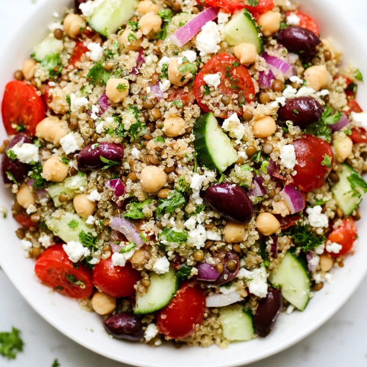A vibrant Greek Power Salad with lentils, quinoa, chickpeas, and fresh vegetables tossed in zesty vinaigrette.  