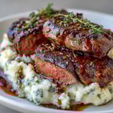 Tender venison steaks served over fluffy swede mash, topped with buttery pan juices for a hearty meal.