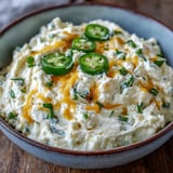 A creamy bowl of Crack Corn Dip garnished with fresh green onions, featuring sweet corn and sharp cheddar, ready for a party.
