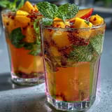 Vibrant alcohol-free sangria featuring ripe mango and peach slices, citrus wheels, and sparkling water for a festive drink.