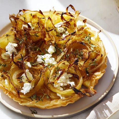 A close-up view of the baked Decadent Caramelized Onion and Goat Cheese Tart with flaky crust.