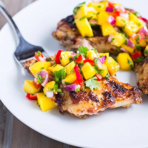 Freshly grilled Mango Salsa Chicken plated, showcasing vibrant mango and red pepper salsa topping.