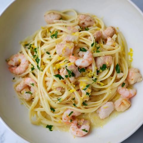 A close-up of Lemon Garlic Shrimp & Chicken Pasta twirled on a fork, showcasing tender shrimp and chicken in a glossy lemon-butter sauce with fresh parsley garnish.