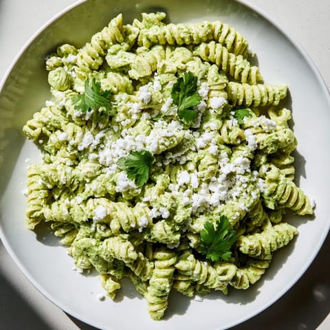 A close-up of creamy Cilantro Lime Chicken Pasta with crumbled feta and fresh cilantro garnish.  