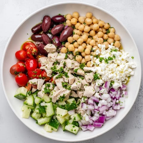 Fresh Mediterranean Chickpea Chicken Salad with juicy chicken, crisp cucumber, tomatoes, feta, and Kalamata olives in zesty dressing.