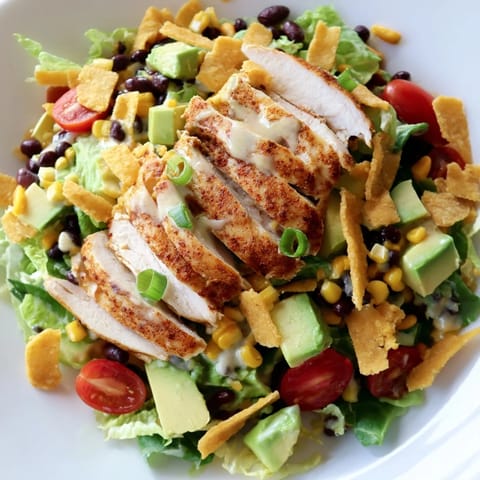 Freshly prepared Crunchy Taco Chicken Salad topped with crunchy taco shell pieces, sliced avocado, and a creamy lime dressing.