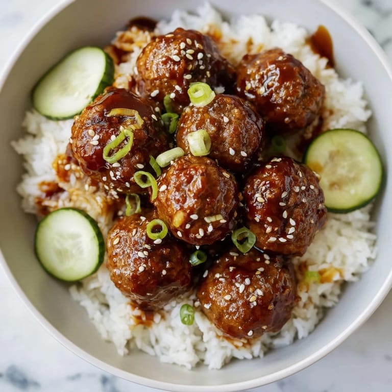 A close-up of savory teriyaki meatball bowls, showing juicy meatballs and vibrant garnishes.
