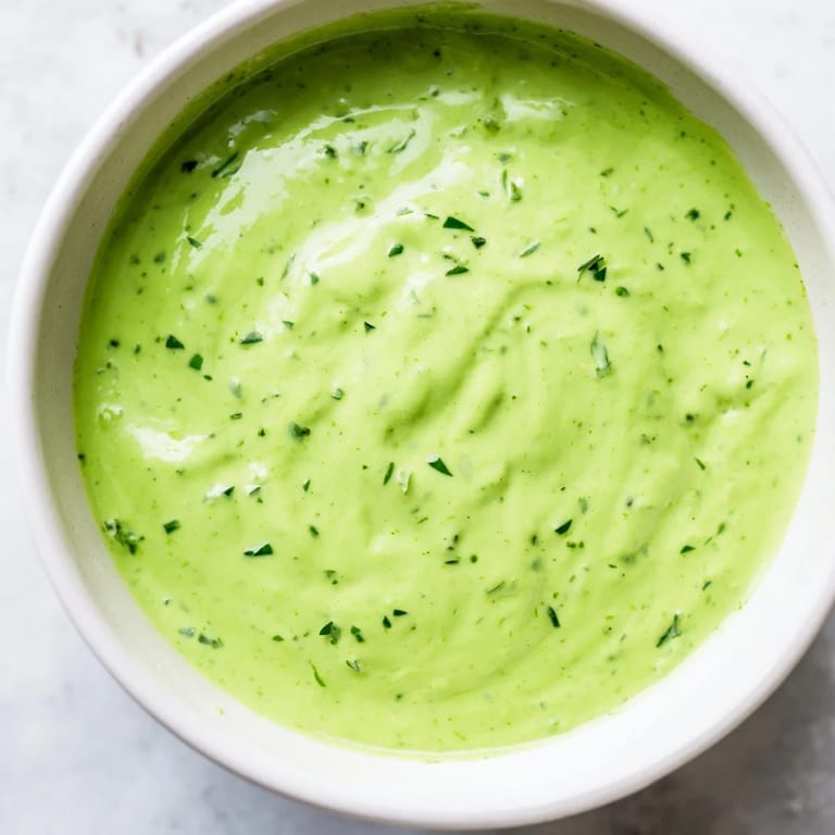 Freshly blended Green Goddess Dressing with a smooth texture and visible flecks of herbs, ready to be served on a vegetable platter.